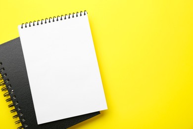 Photo of Notebooks on yellow background, top view. Space for text