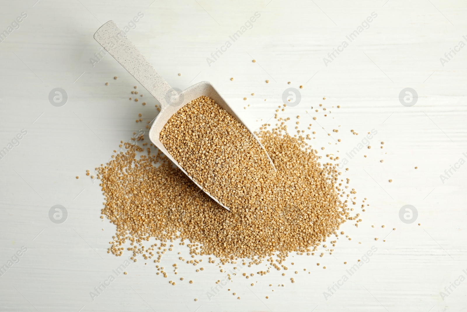 Photo of Scoop with quinoa on white wooden table, flat lay