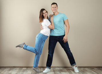 Happy young couple dancing near beige wall