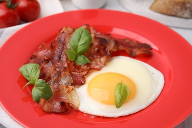 Photo of Fried egg, bacon and basil on table, closeup