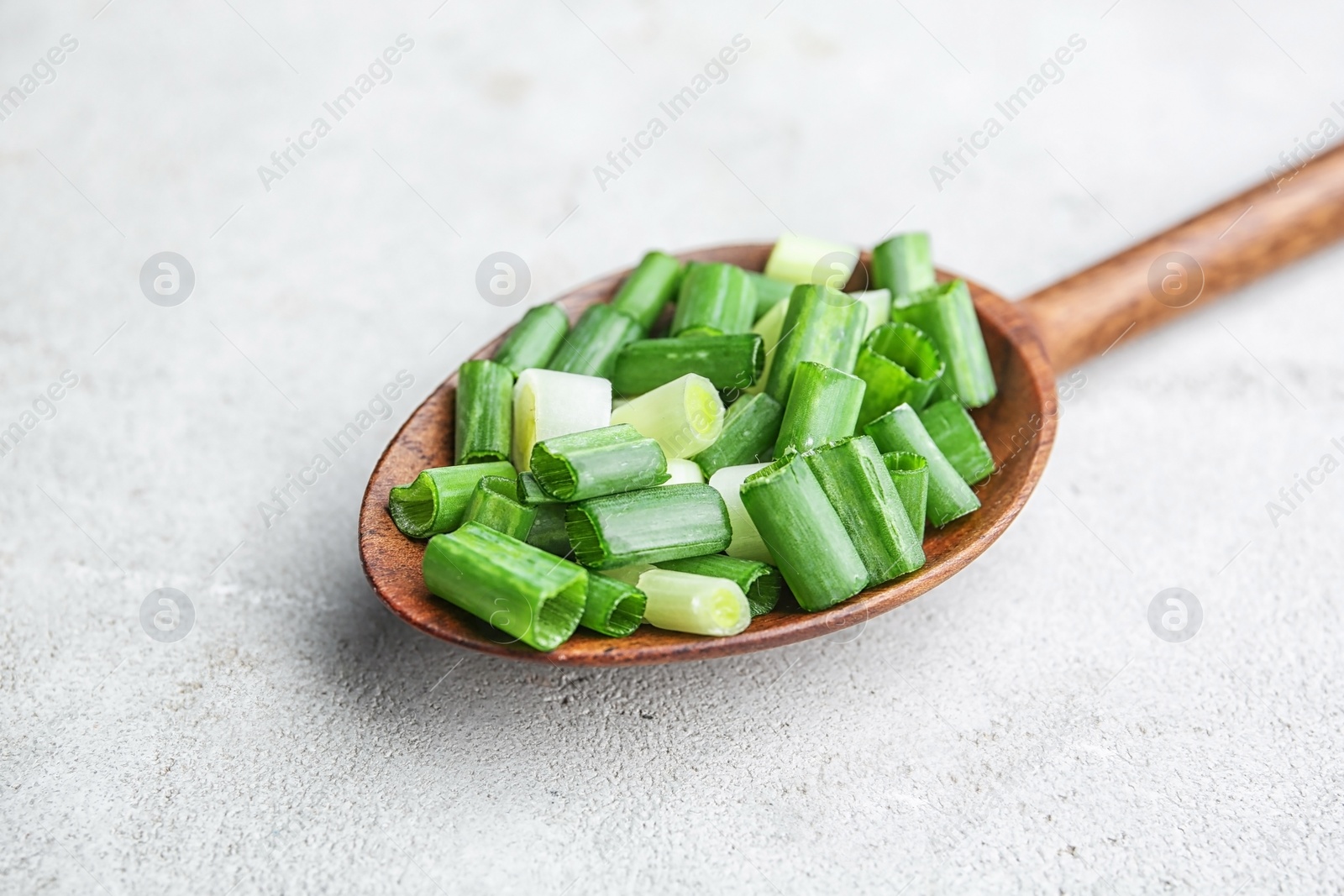 Photo of Spoon with chopped green onion on table