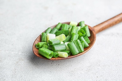 Spoon with chopped green onion on table