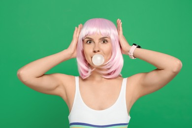 Photo of Beautiful woman blowing bubble gum on green background