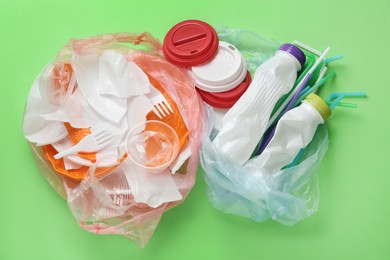 Photo of Pile of different plastic items on green background, flat lay