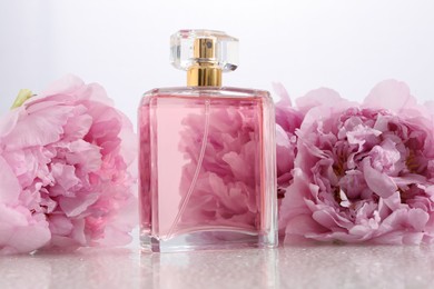Photo of Luxury perfume and floral decor on plastic surface