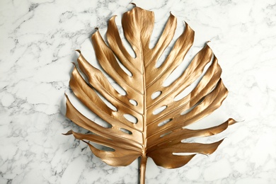 Photo of Painted tropical Monstera leaf on marble background, top view