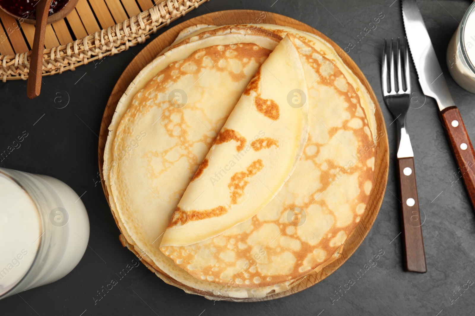 Photo of Flat lay composition with fresh thin pancakes on black table