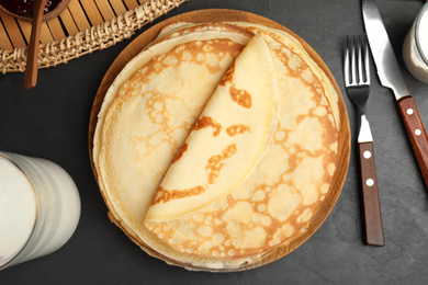 Flat lay composition with fresh thin pancakes on black table