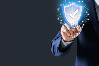 Cyber insurance concept. Man using virtual screen with shield illustration as symbol of protection, closeup