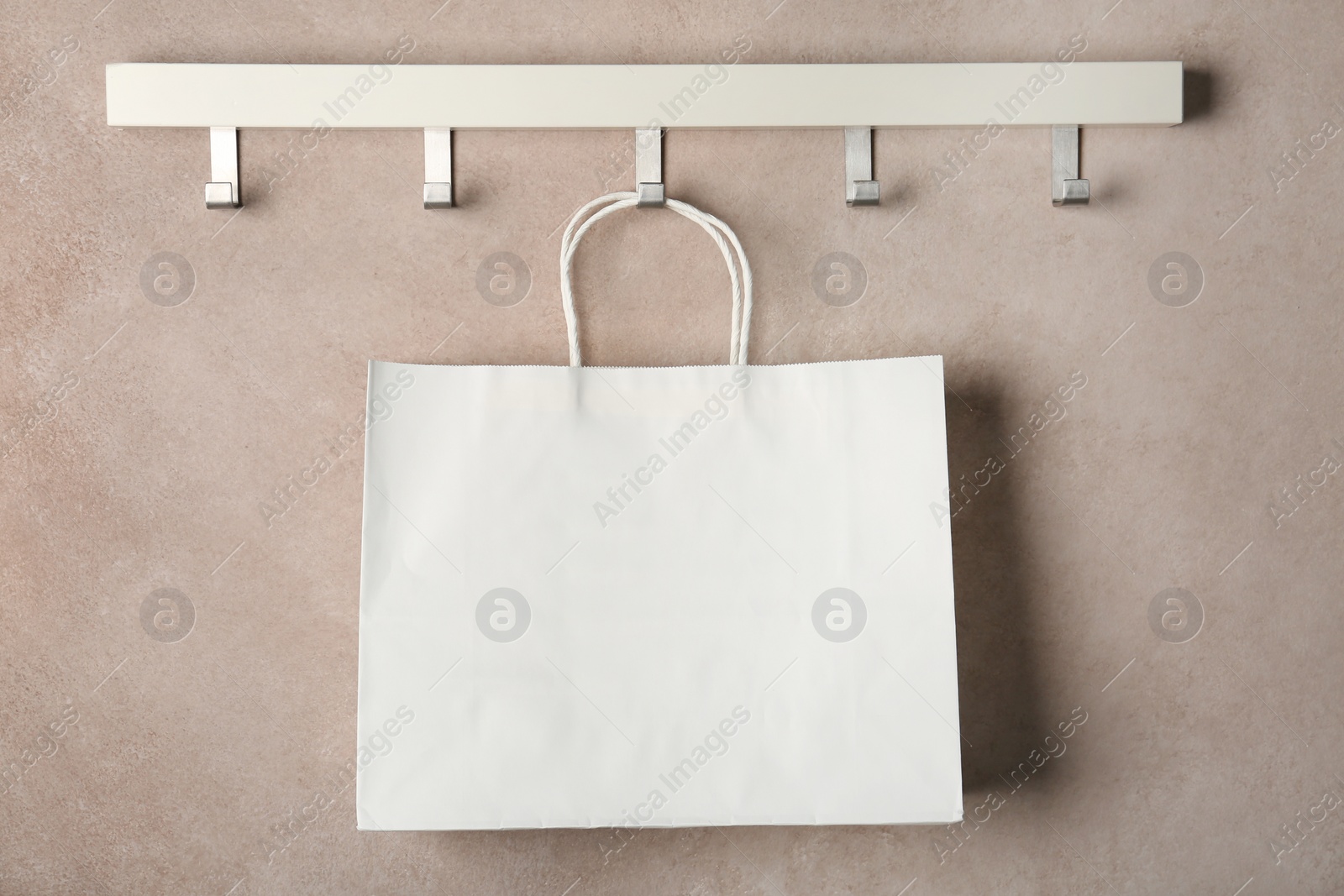 Photo of Rack with paper shopping bag on color wall