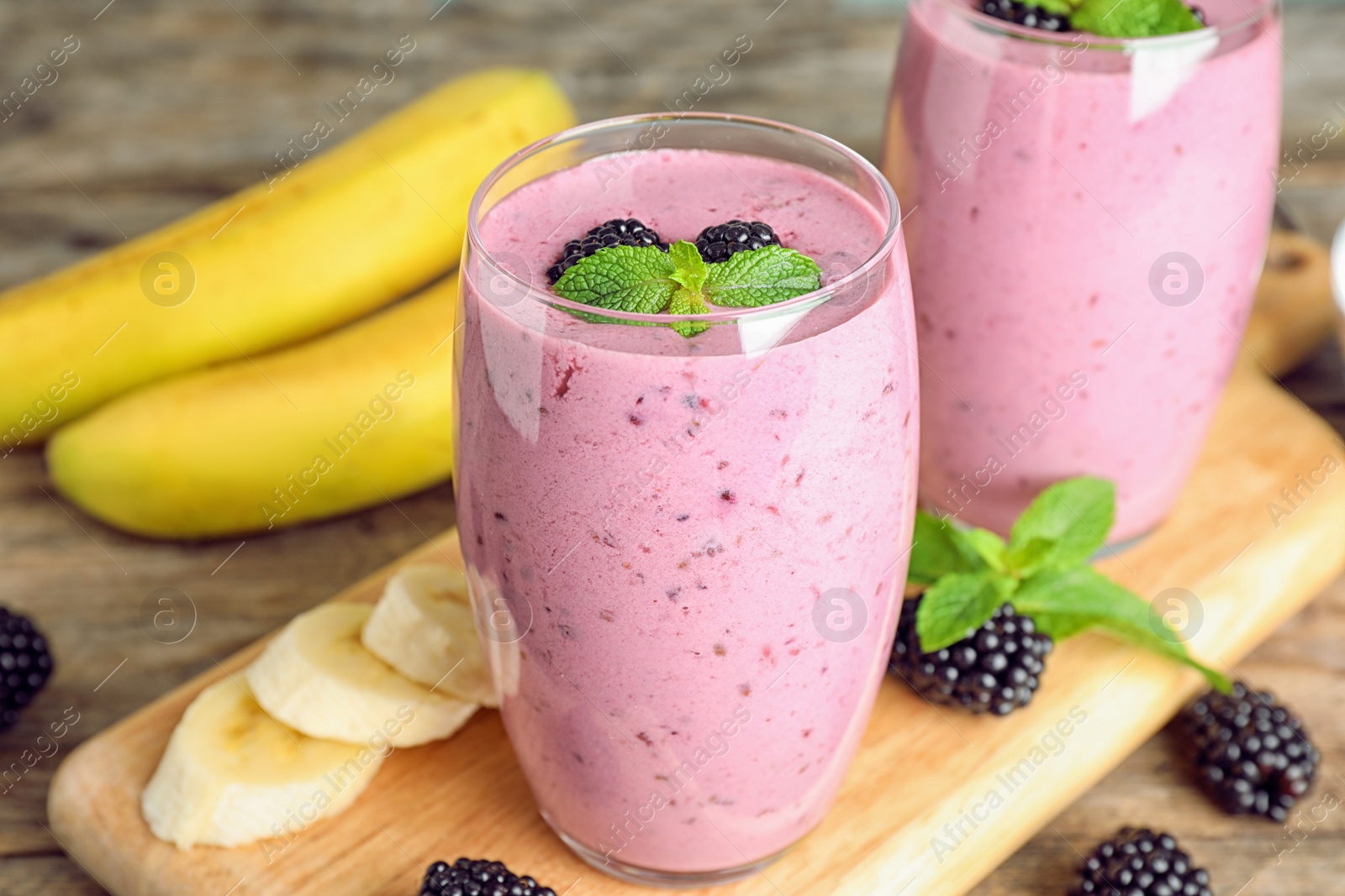 Photo of Delicious blackberry smoothie in glasses on wooden table