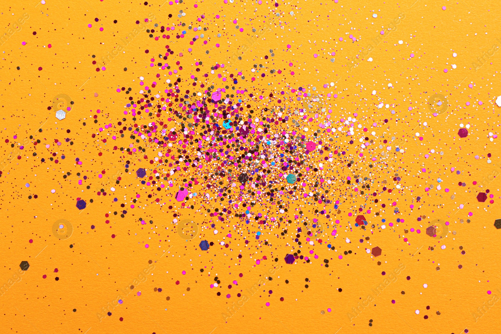 Photo of Shiny bright glitter on orange background, flat lay