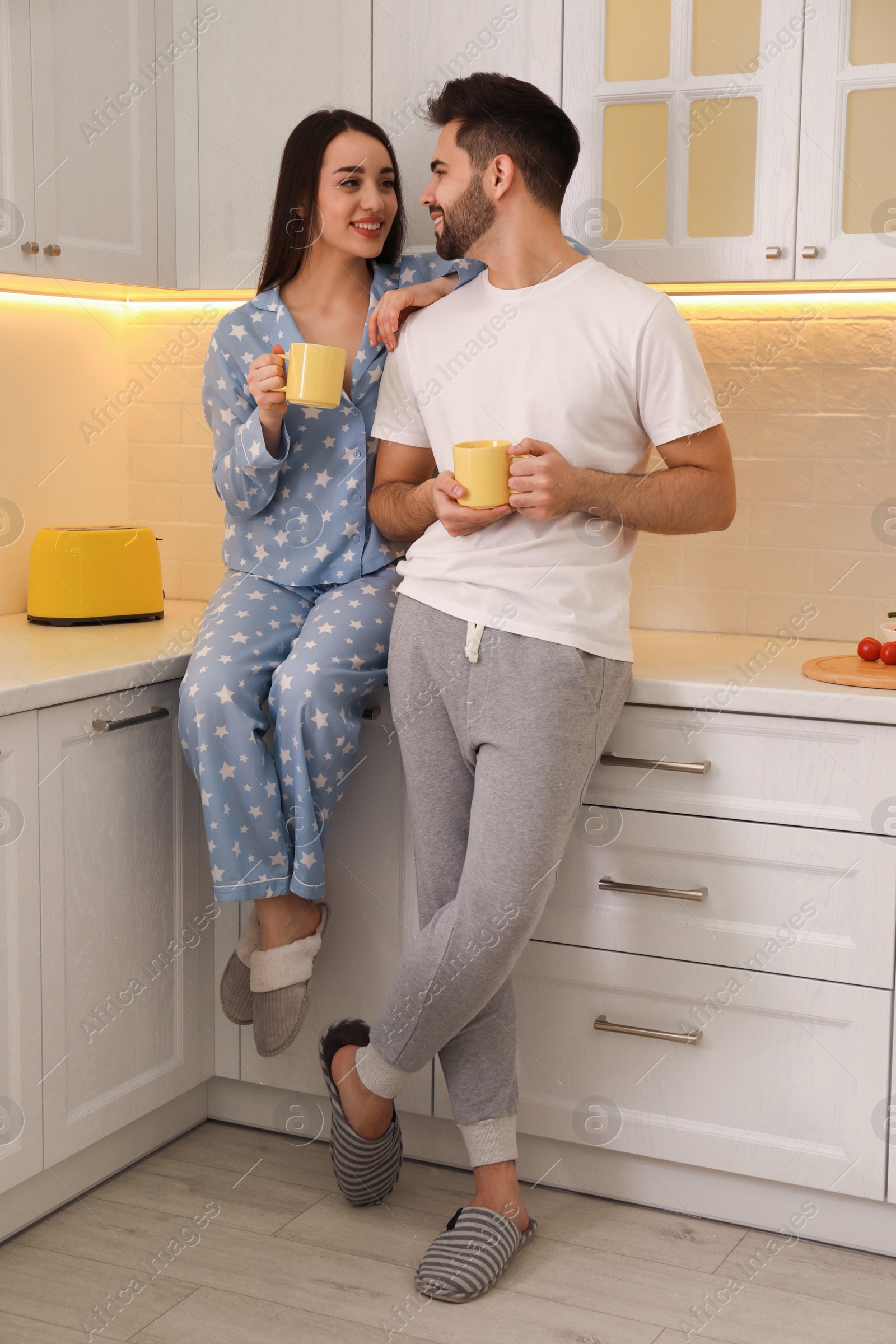 Photo of Happy couple in pajamas having breakfast at home