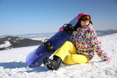 Photo of Young woman with snowboard on hill. Winter vacation