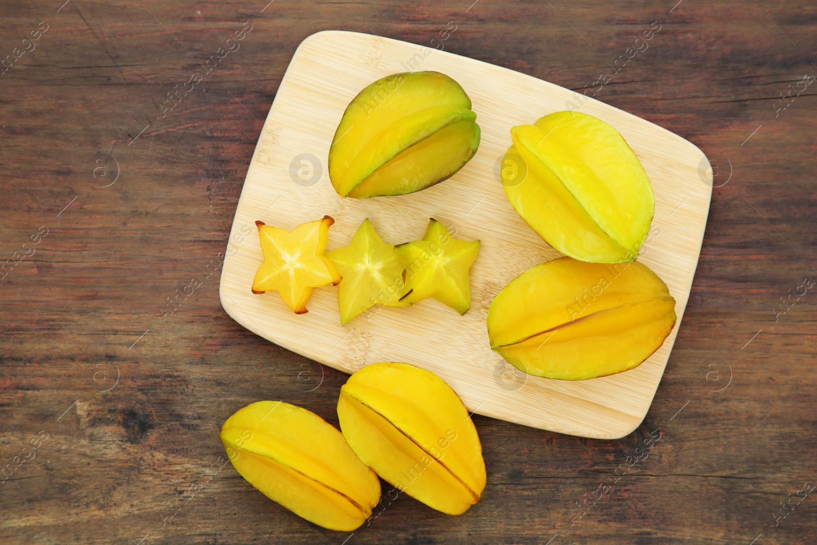 Photo of Cut and whole delicious ripe carambolas on wooden table, flat lay