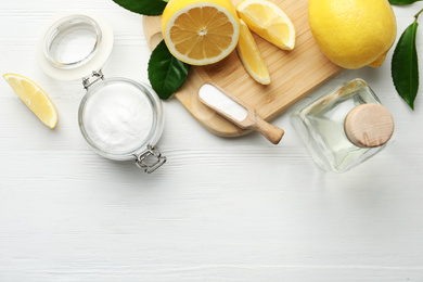 Photo of Baking soda, vinegar and cut lemons on white wooden table, flat lay. Space for text