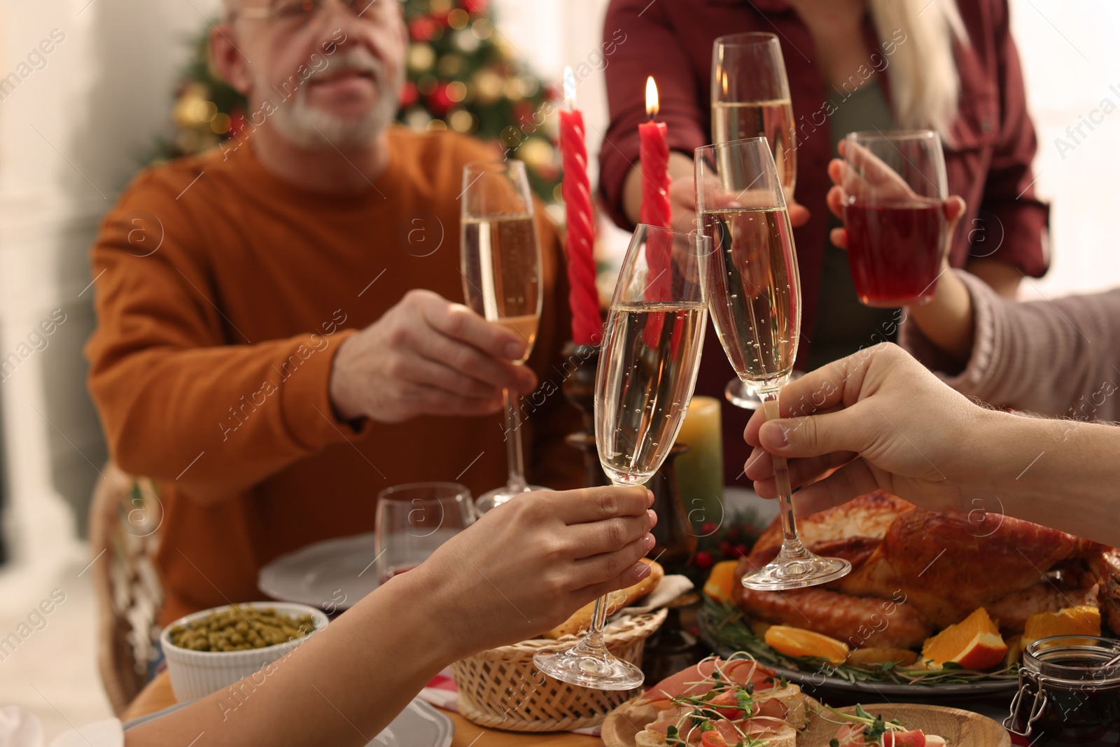 Photo of Family clinking glasses of drinks at festive dinner, focus on hands. Christmas celebration