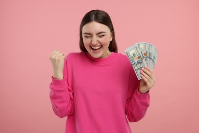 Happy woman with dollar banknotes on pink background