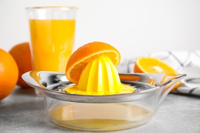 Fresh ripe oranges and squeezer on grey table