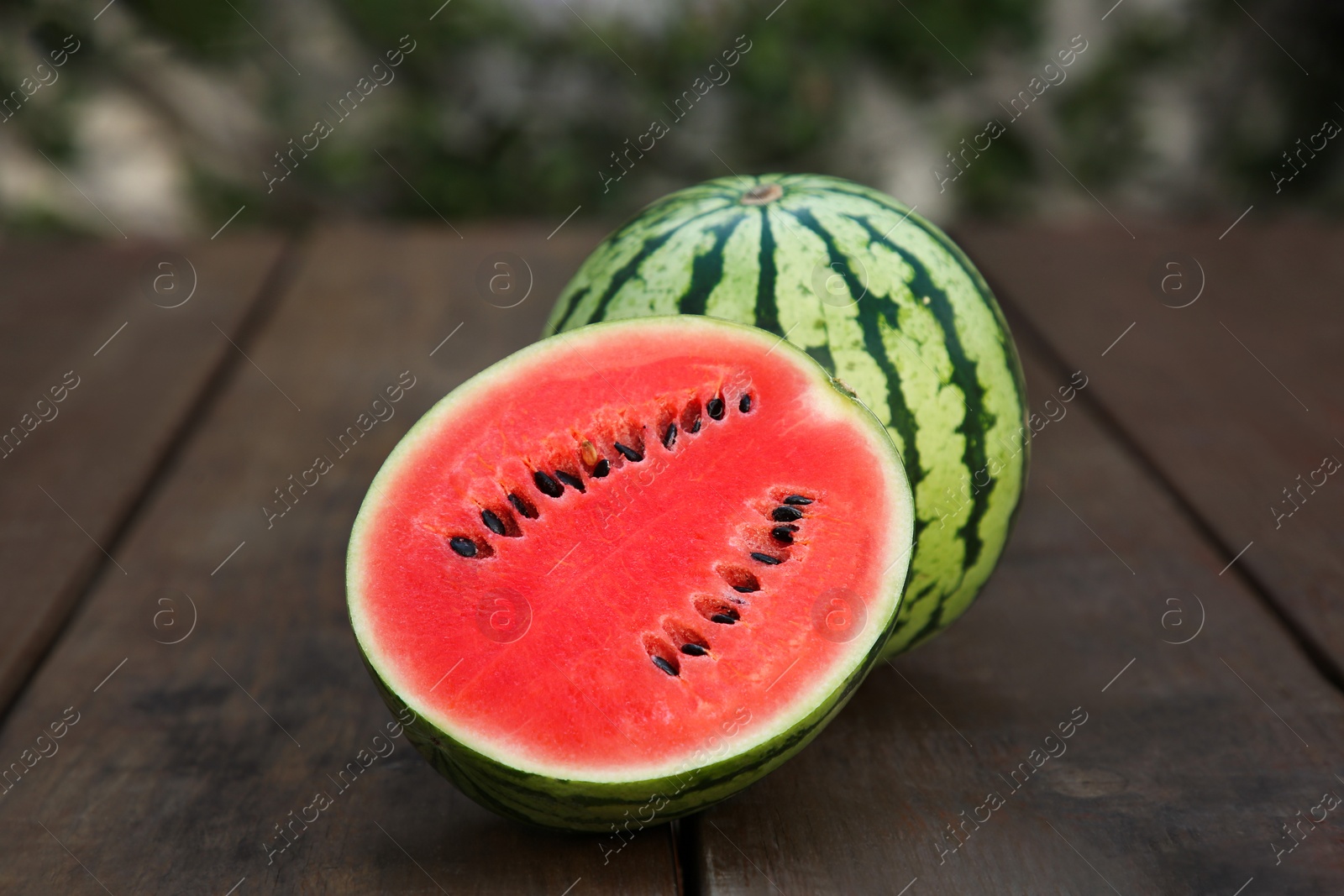 Photo of Delicious cut and whole ripe watermelons on wooden table