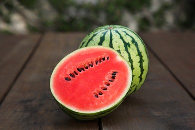 Delicious cut and whole ripe watermelons on wooden table