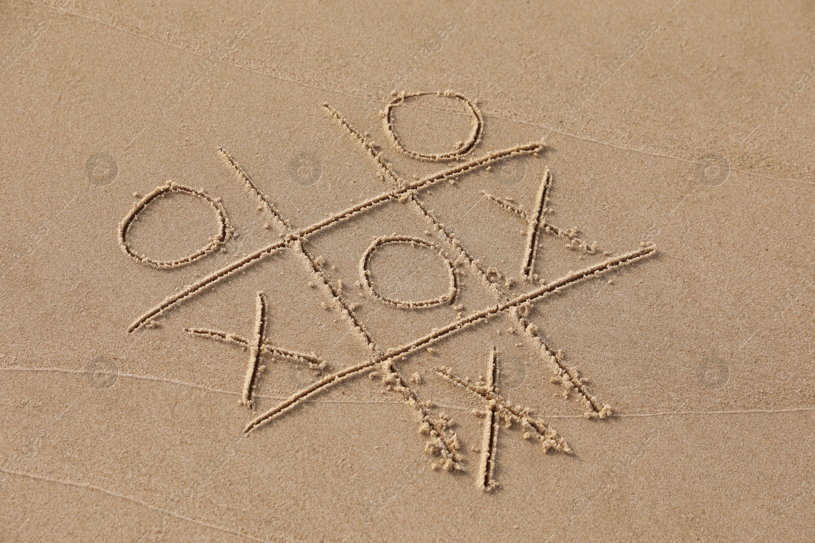 Photo of Tic tac toe game drawn on sandy beach, above view