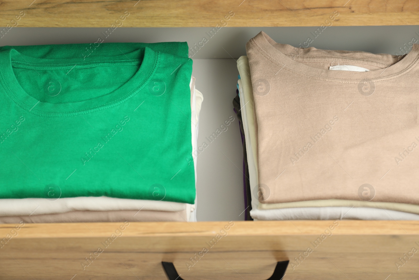 Photo of Stacks of different folded shirts in drawer. Organizing clothes