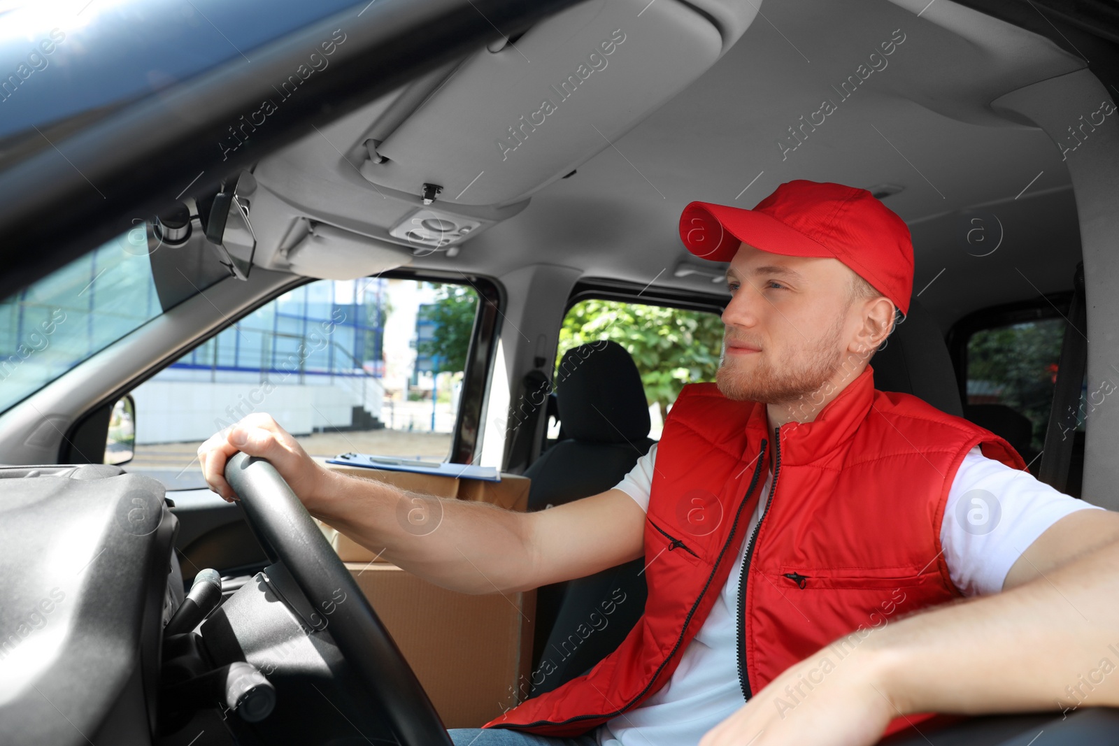 Photo of Young courier with parcels in delivery car