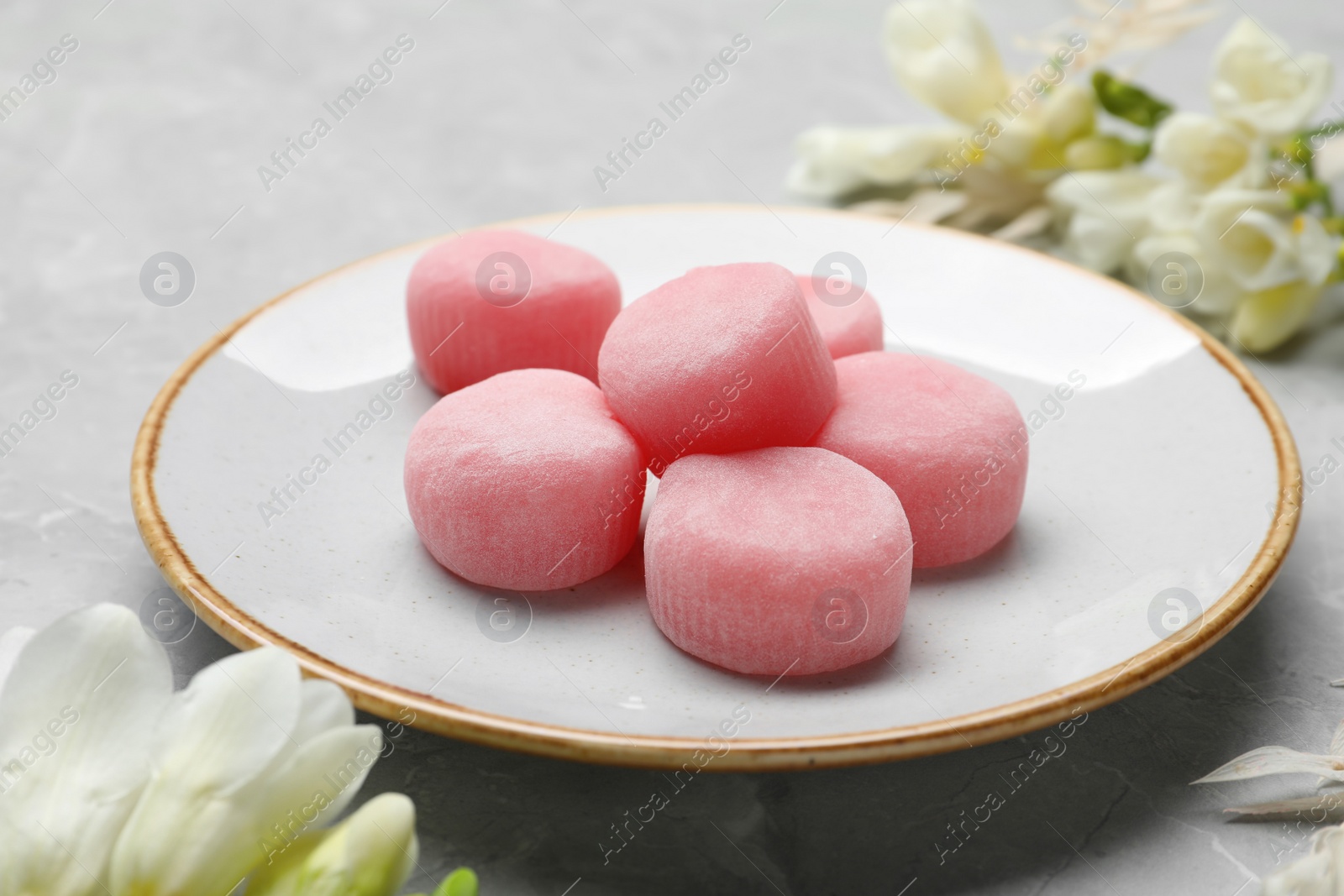 Photo of Delicious mochi and flowers on light grey marble table. Traditional Japanese dessert