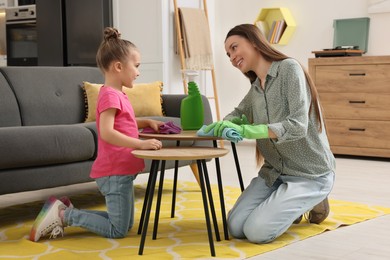 Photo of Spring cleaning. Mother and daughter tidying up living room together