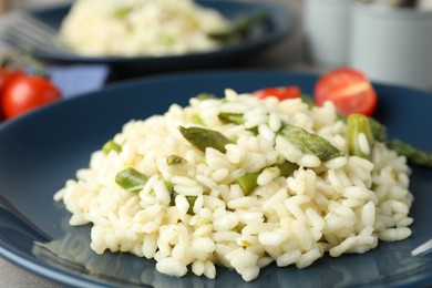 Photo of Delicious risotto with asparagus in plate, closeup