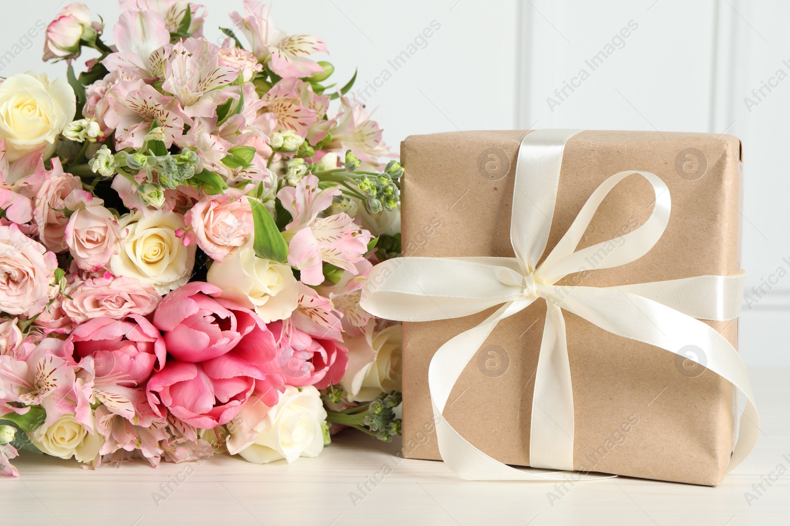 Photo of Happy Mother's Day. Gift box and bouquet of beautiful flowers on white table