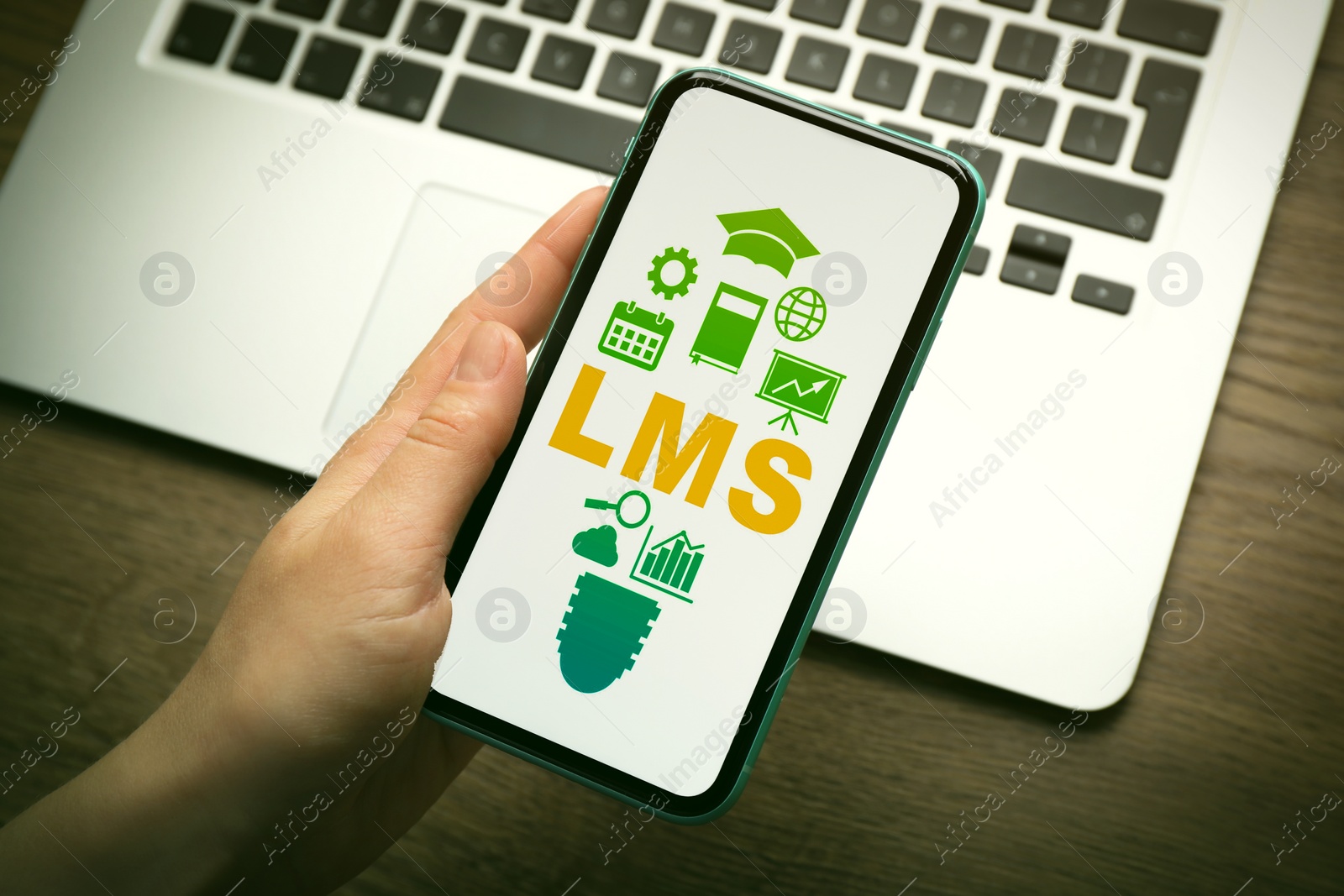 Image of Learning management system. Woman using mobile phone at wooden table, closeup. Different icons and abbreviation LMS on screen
