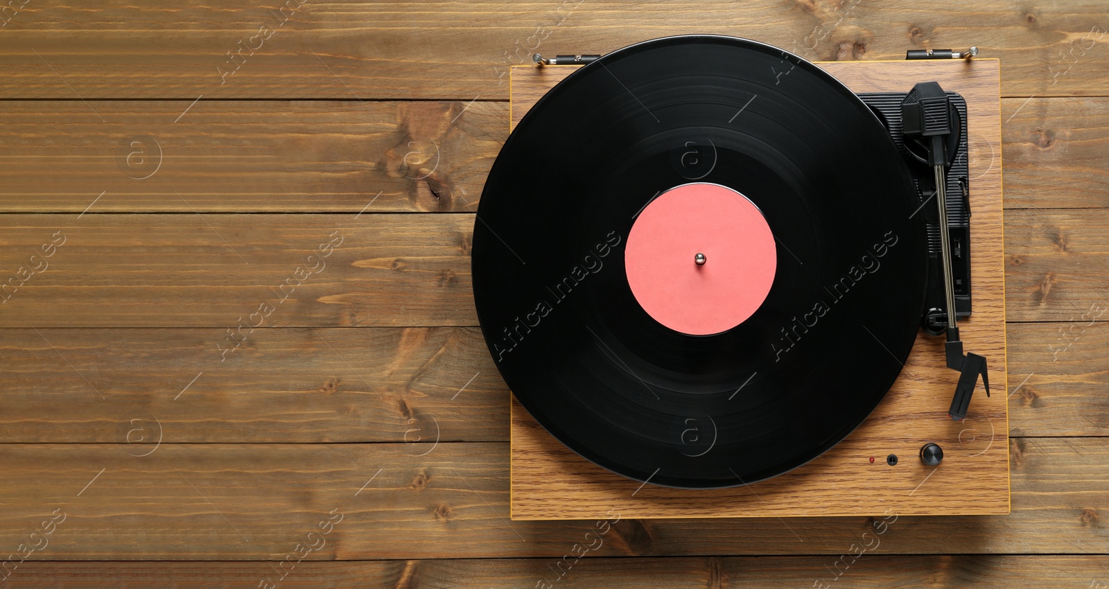 Photo of Turntable with vinyl record on wooden background, top view