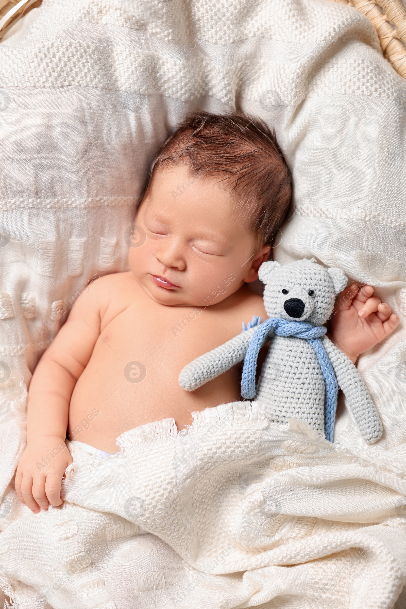 Photo of Cute newborn baby sleeping with toy bear on white blanket, top view