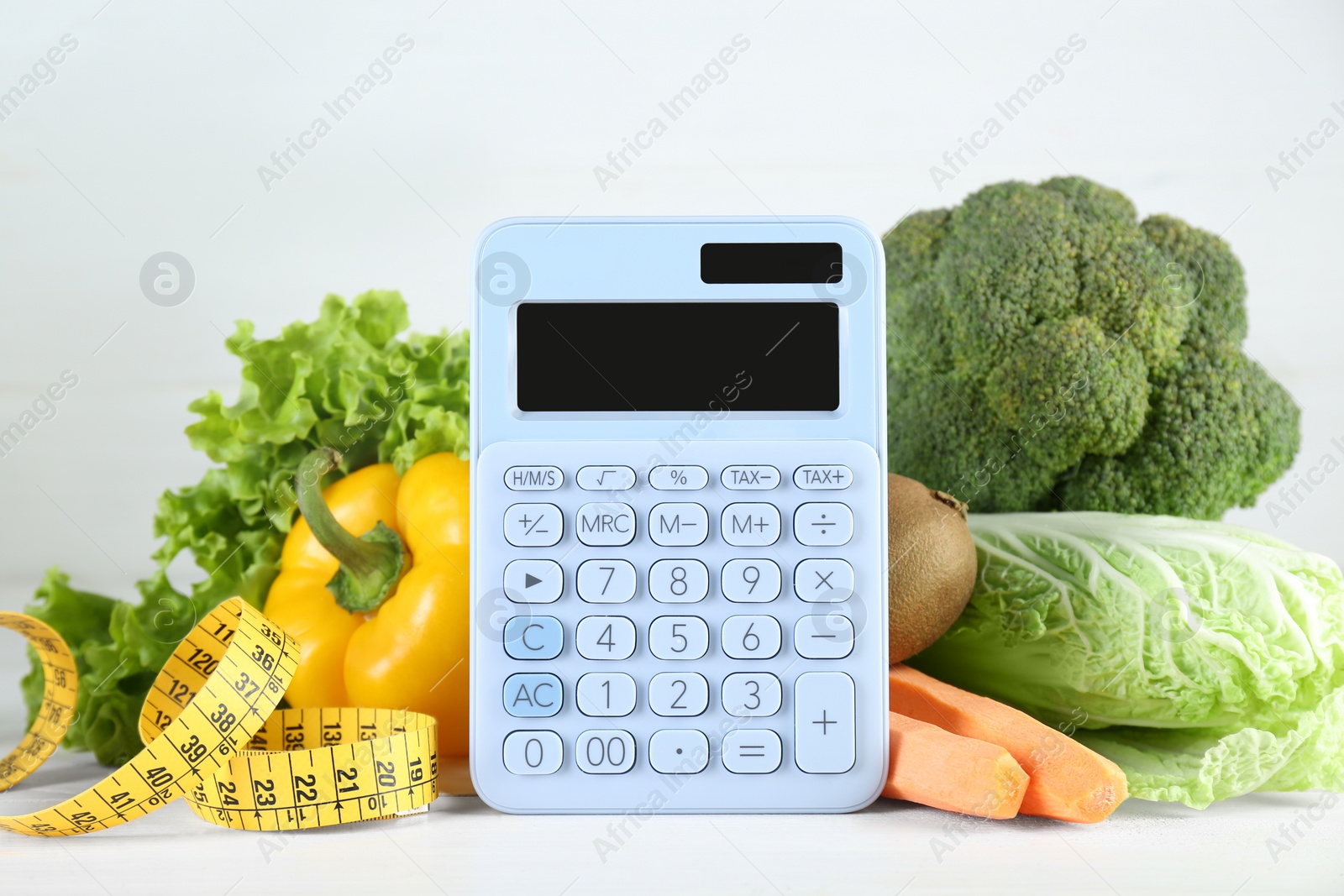 Photo of Calculator and food products on white wooden table. Weight loss concept