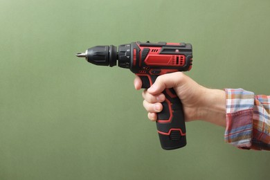 Photo of Handyman holding electric screwdriver on pale green background, closeup