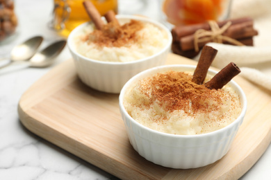 Photo of Delicious rice pudding with cinnamon on wooden board