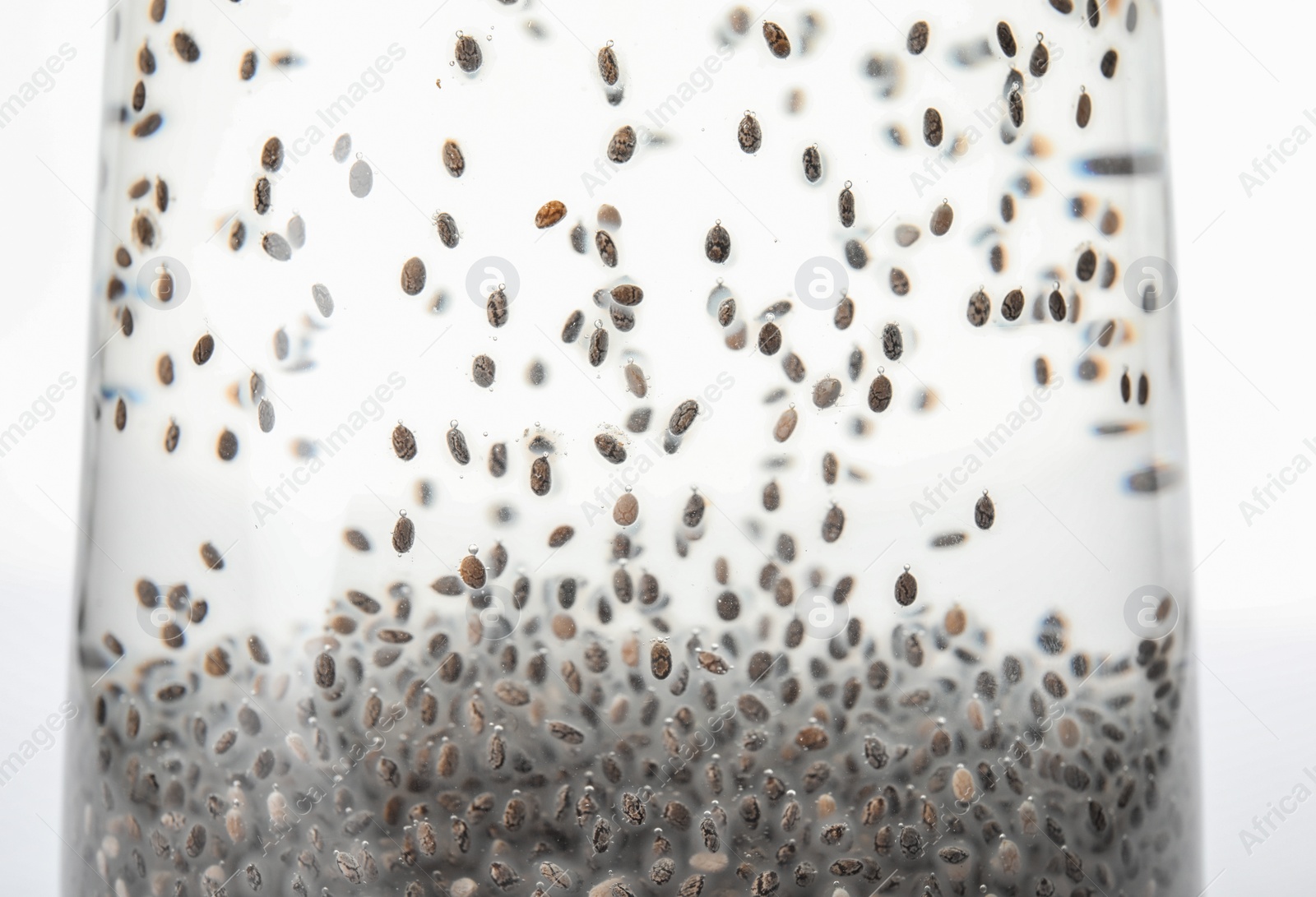 Photo of Glass of water with chia seeds on white background, closeup