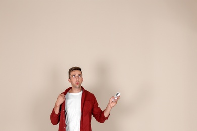 Photo of Young man operating air conditioner with remote control on light background