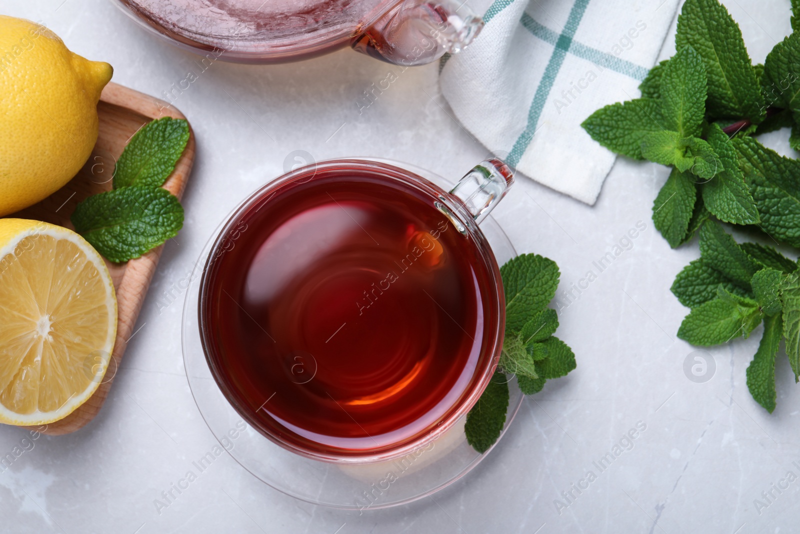 Photo of Cup of hot aromatic tea with mint and lemon on light grey table, flat lay