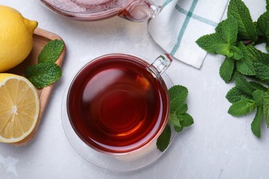 Cup of hot aromatic tea with mint and lemon on light grey table, flat lay