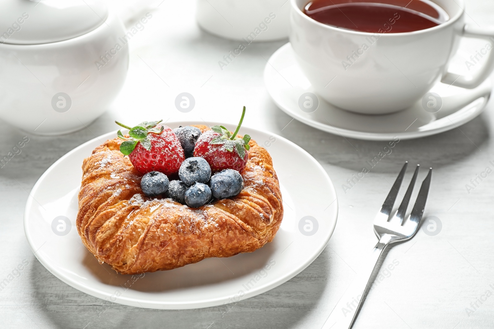 Photo of Fresh delicious puff pastry with sweet berries served on light table