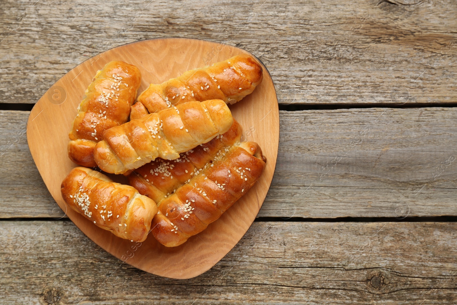 Photo of Delicious sausage rolls on wooden table, top view. Space for text