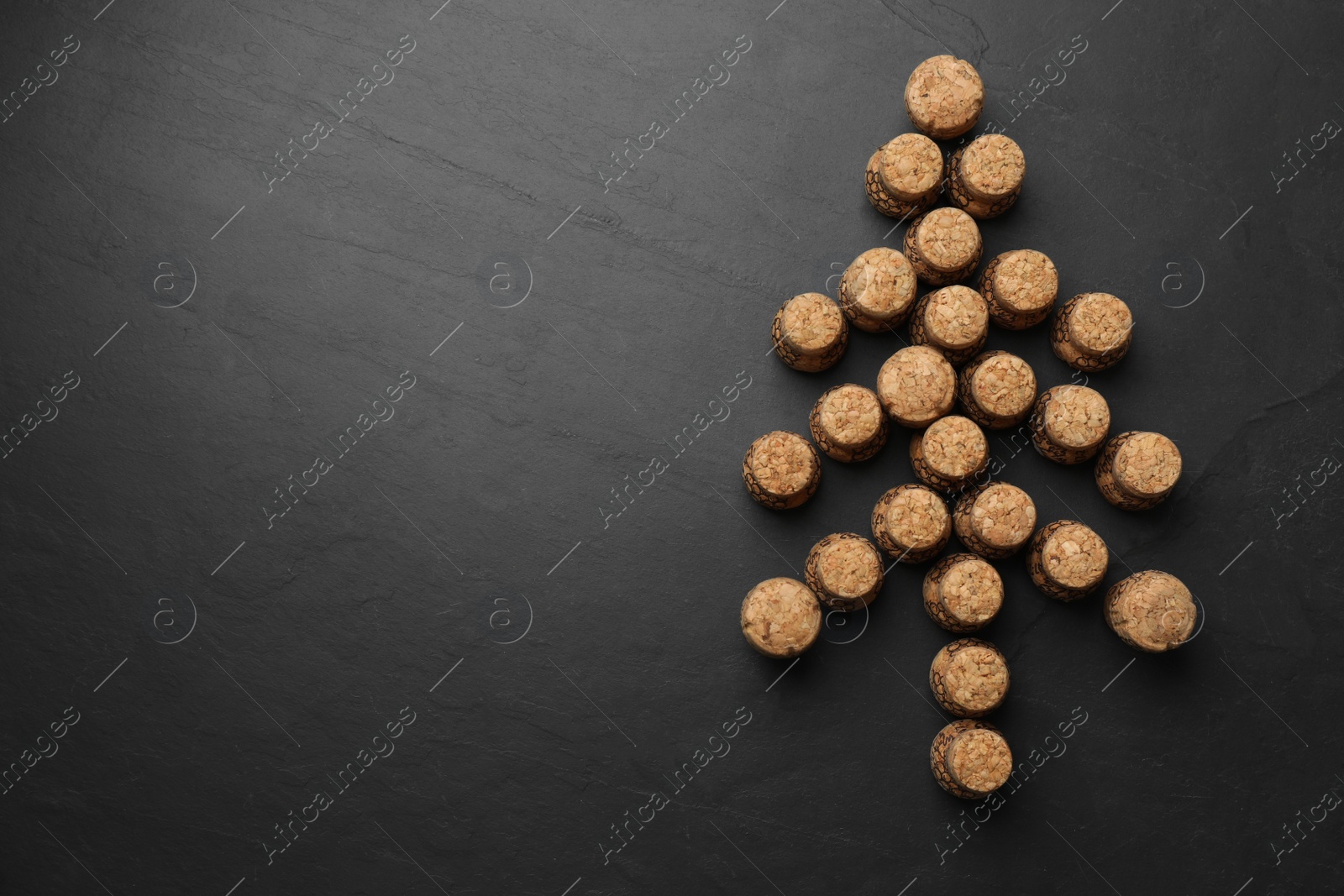 Photo of Christmas tree made of sparkling wine corks on black background, flat lay. Space for text