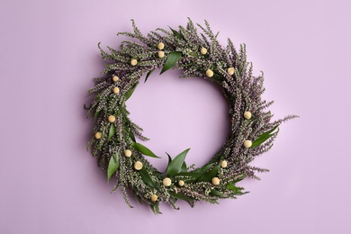 Beautiful heather wreath on violet background, top view. Autumnal flowers