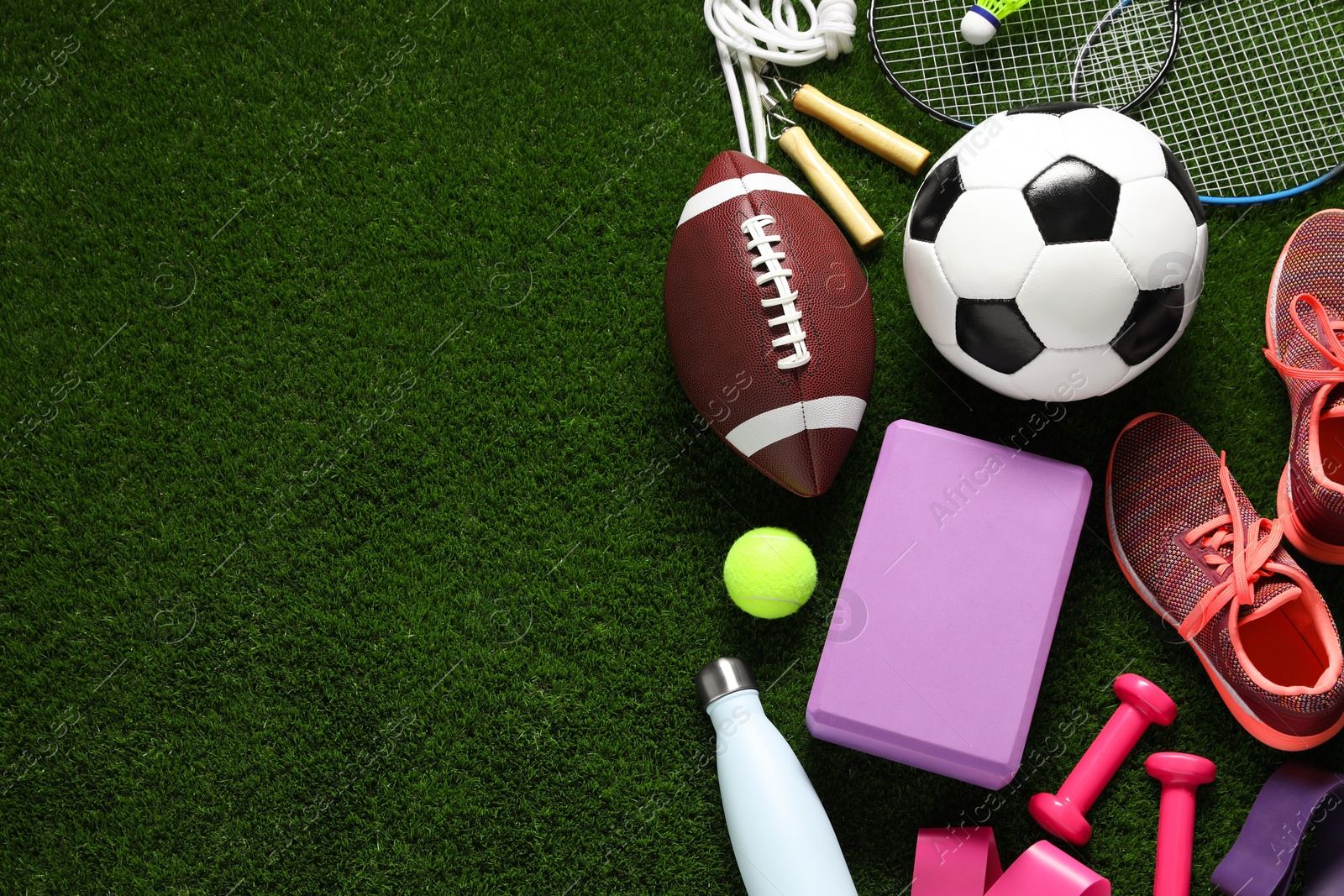 Photo of Different sports equipment on green grass, flat lay. Space for text