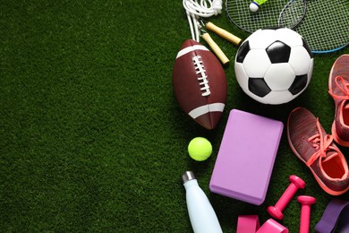 Photo of Different sports equipment on green grass, flat lay. Space for text