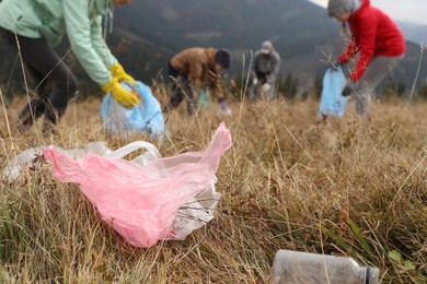 People collecting garbage in nature, focus on plastic trash