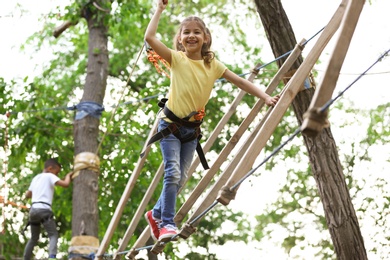 Little girl climbing in adventure park. Summer camp